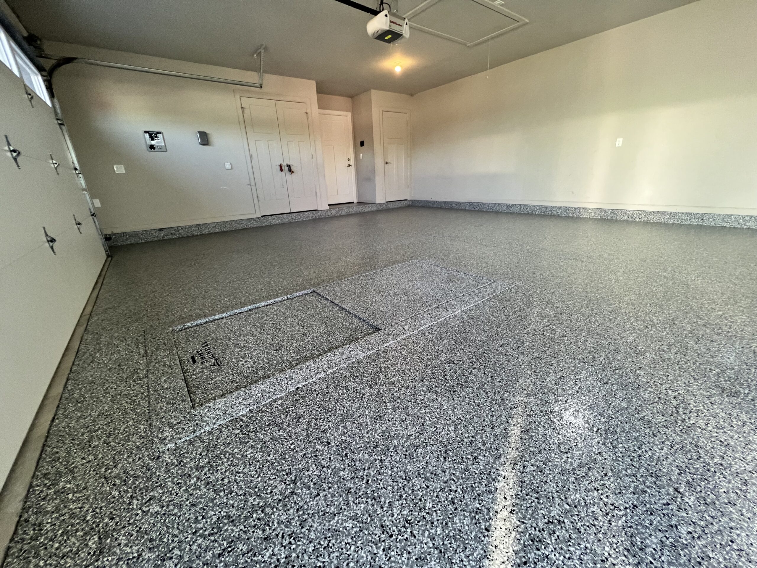 Tan and brown flake epoxy floor in a large residential garage with smooth seamless finish