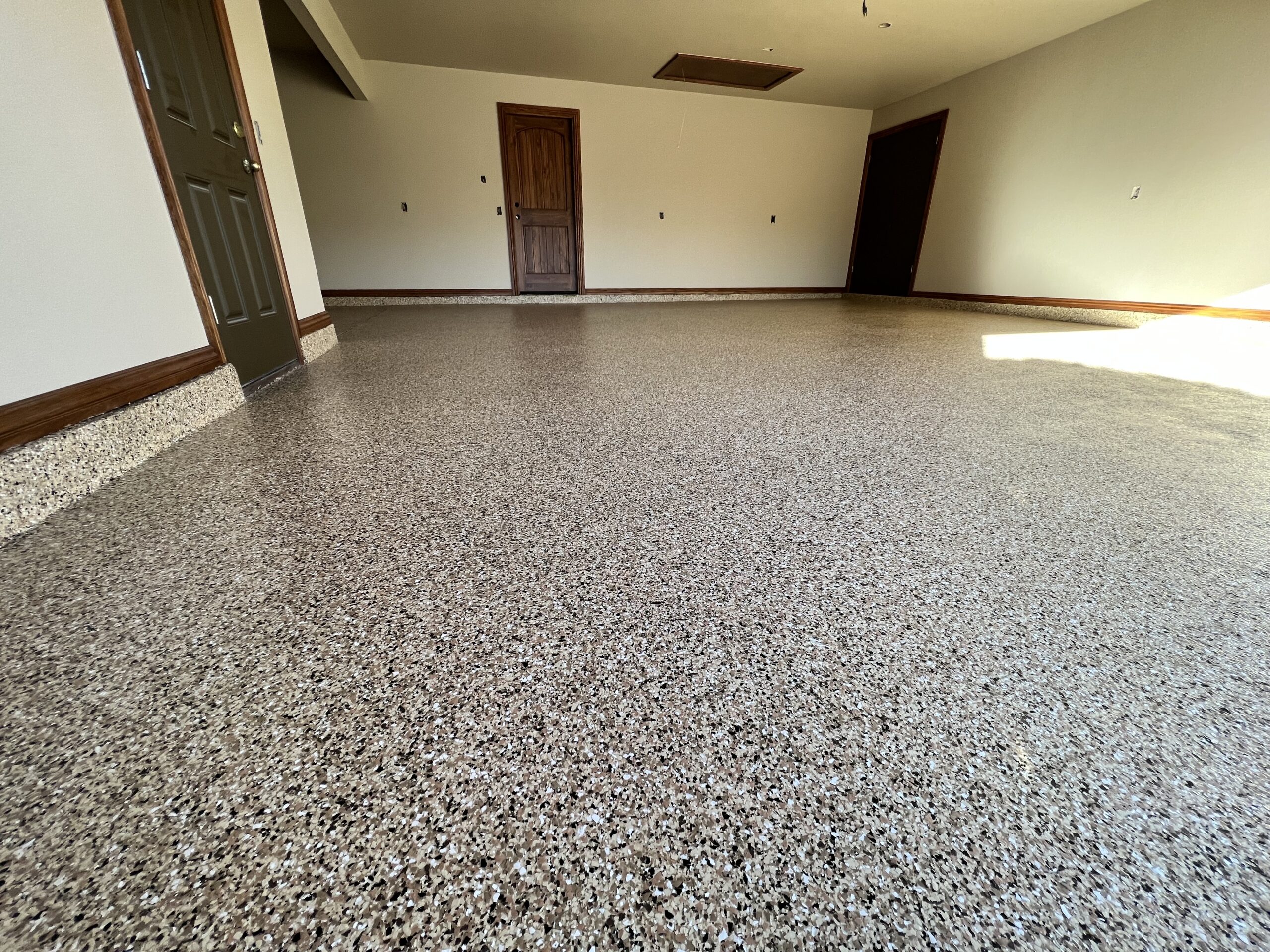 Grey flake epoxy garage floor with seamless finish and clean concrete stem walls