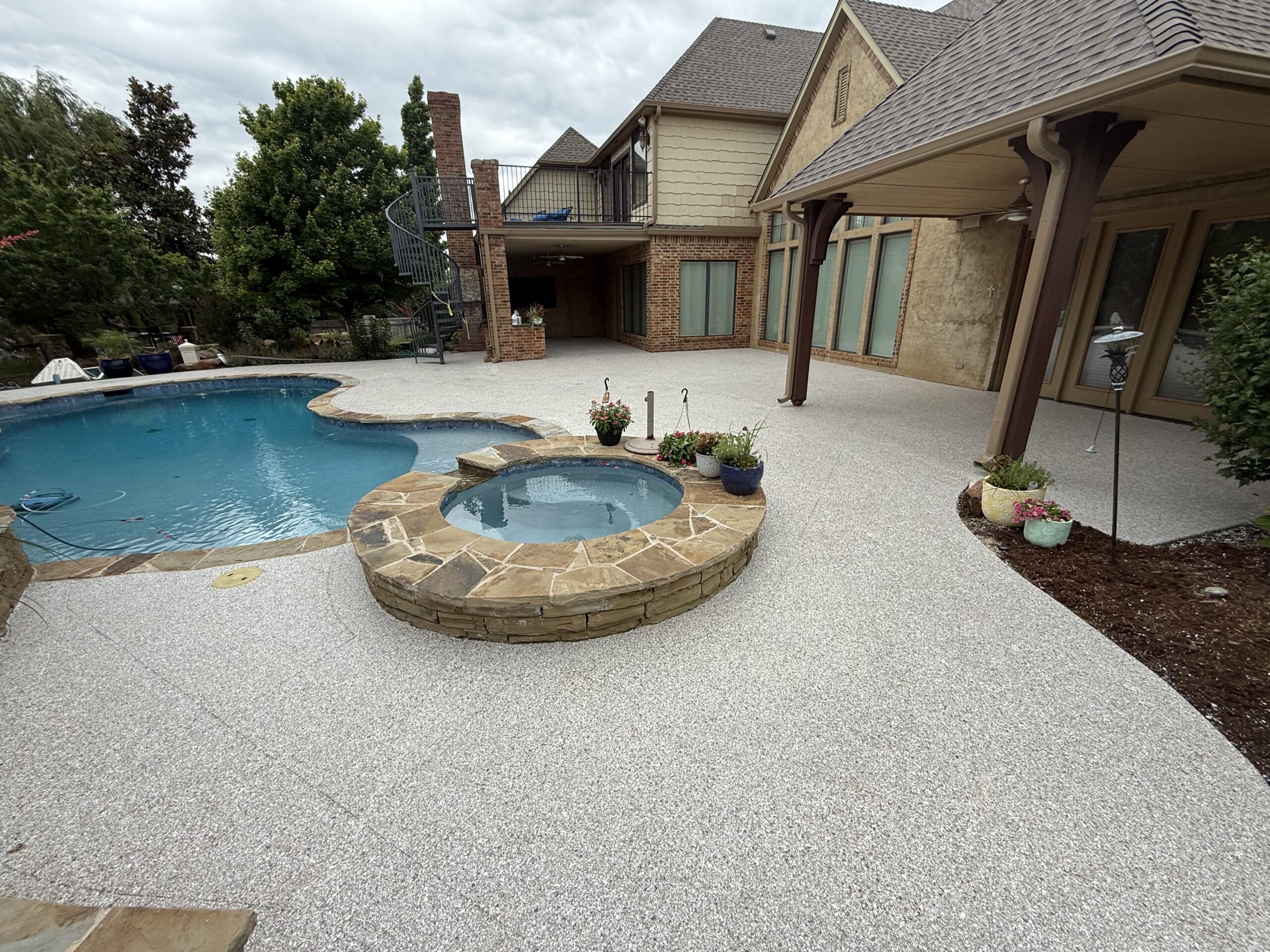 Polyaspartic pool deck coating around residential backyard pool and hot tub