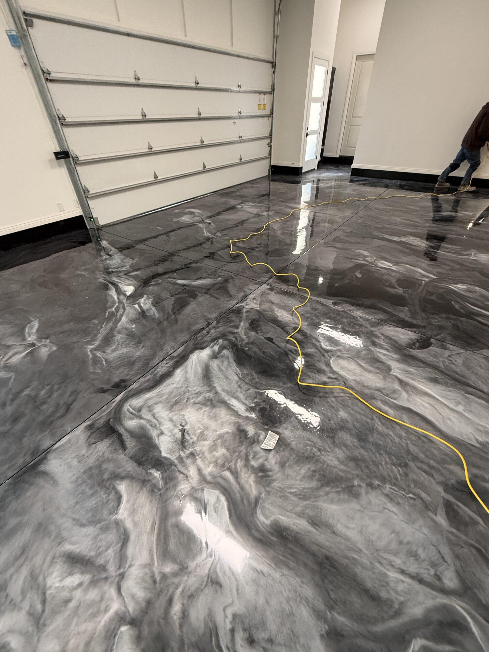Metallic epoxy garage floor with glossy gray marbling and natural light reflections
