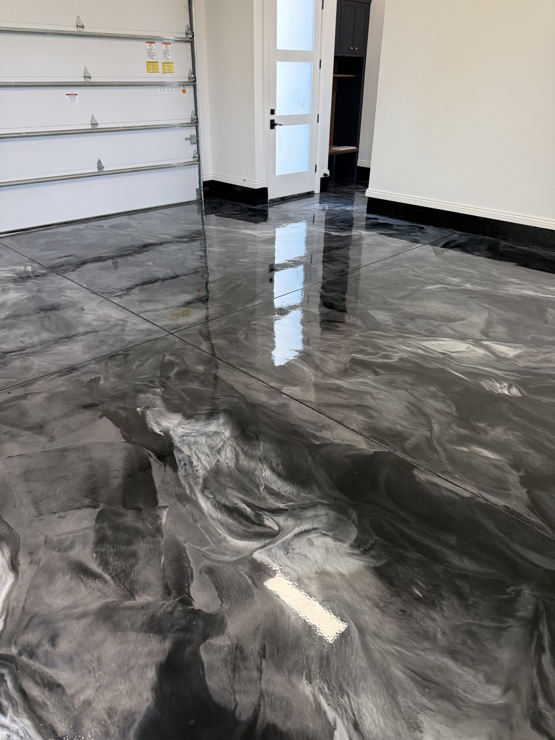 Metallic epoxy garage floor with high-gloss gray marbled finish during installation