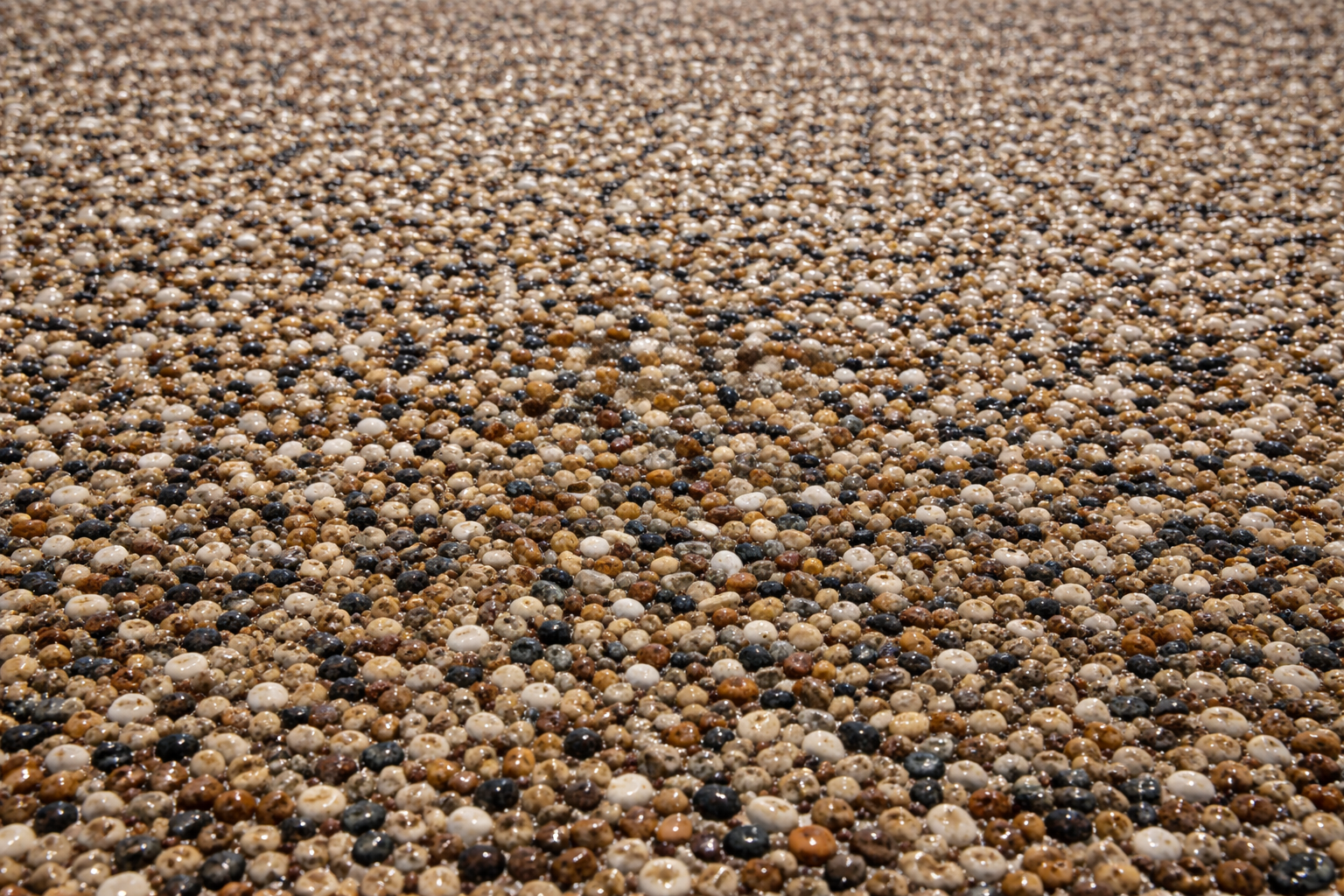 Close up of pebblestone epoxy coating showing natural stone blend texture on exterior concrete surface.